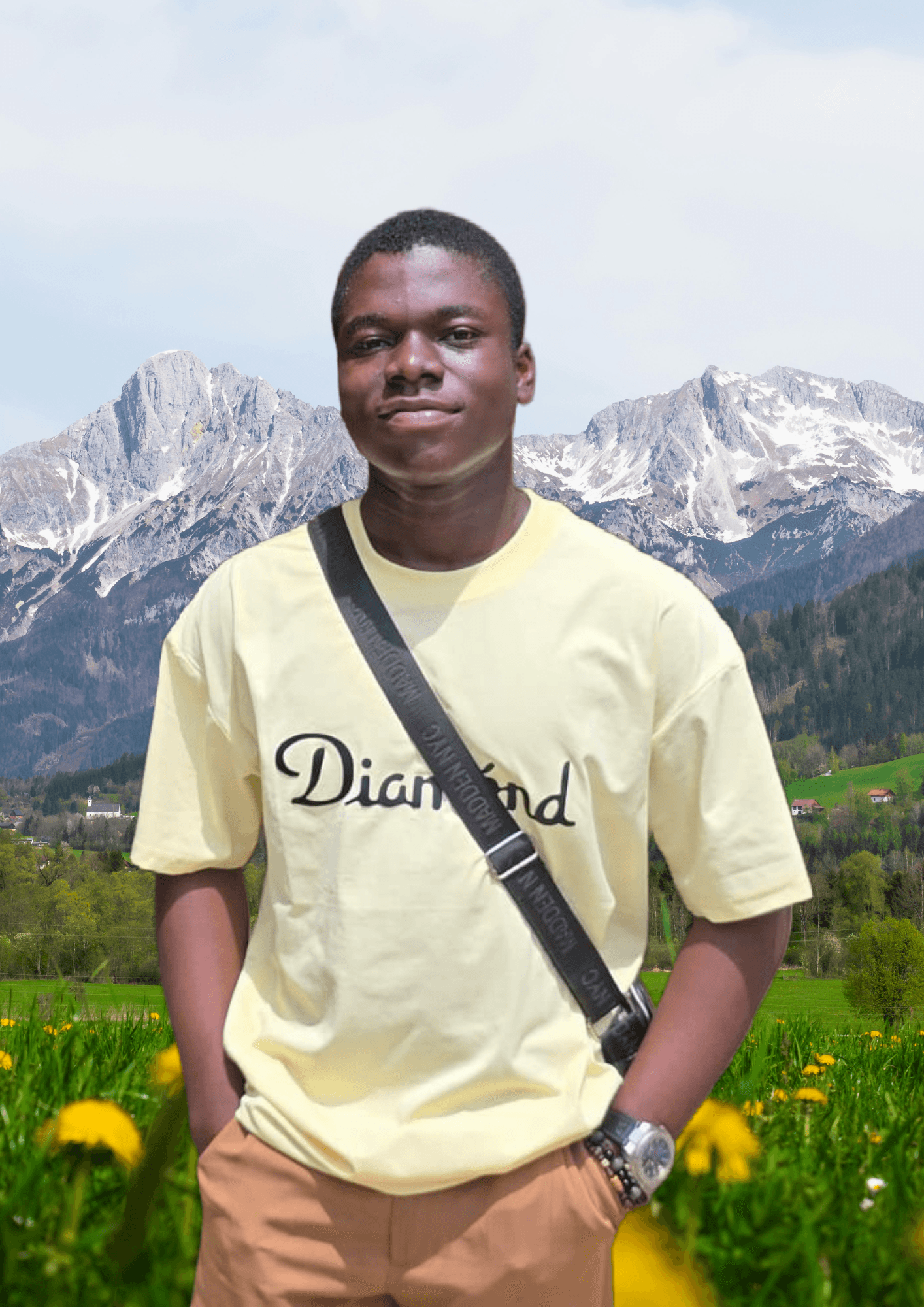Young man in a yellow t-shirt posing in a flower field before snow-capped mountains.